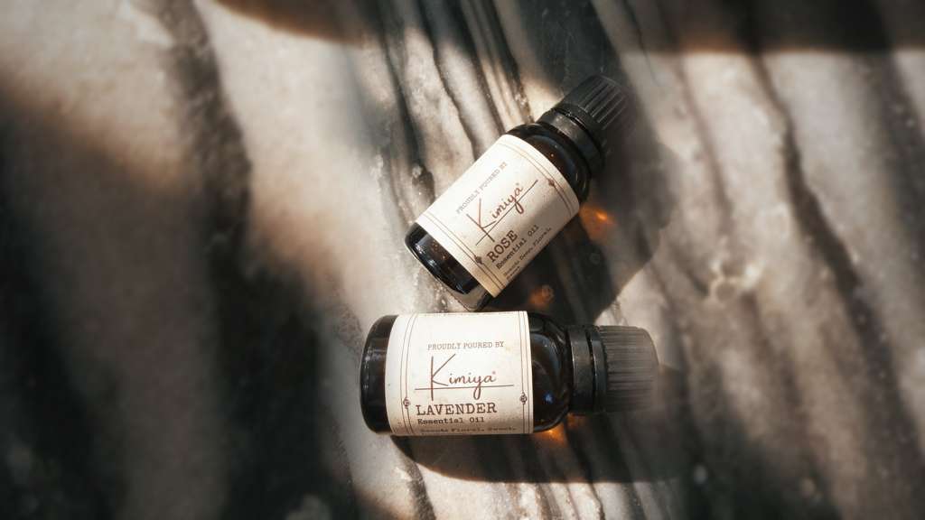Kimiya Rose and Lavender essential oil bottles resting on a sunlit stone surface